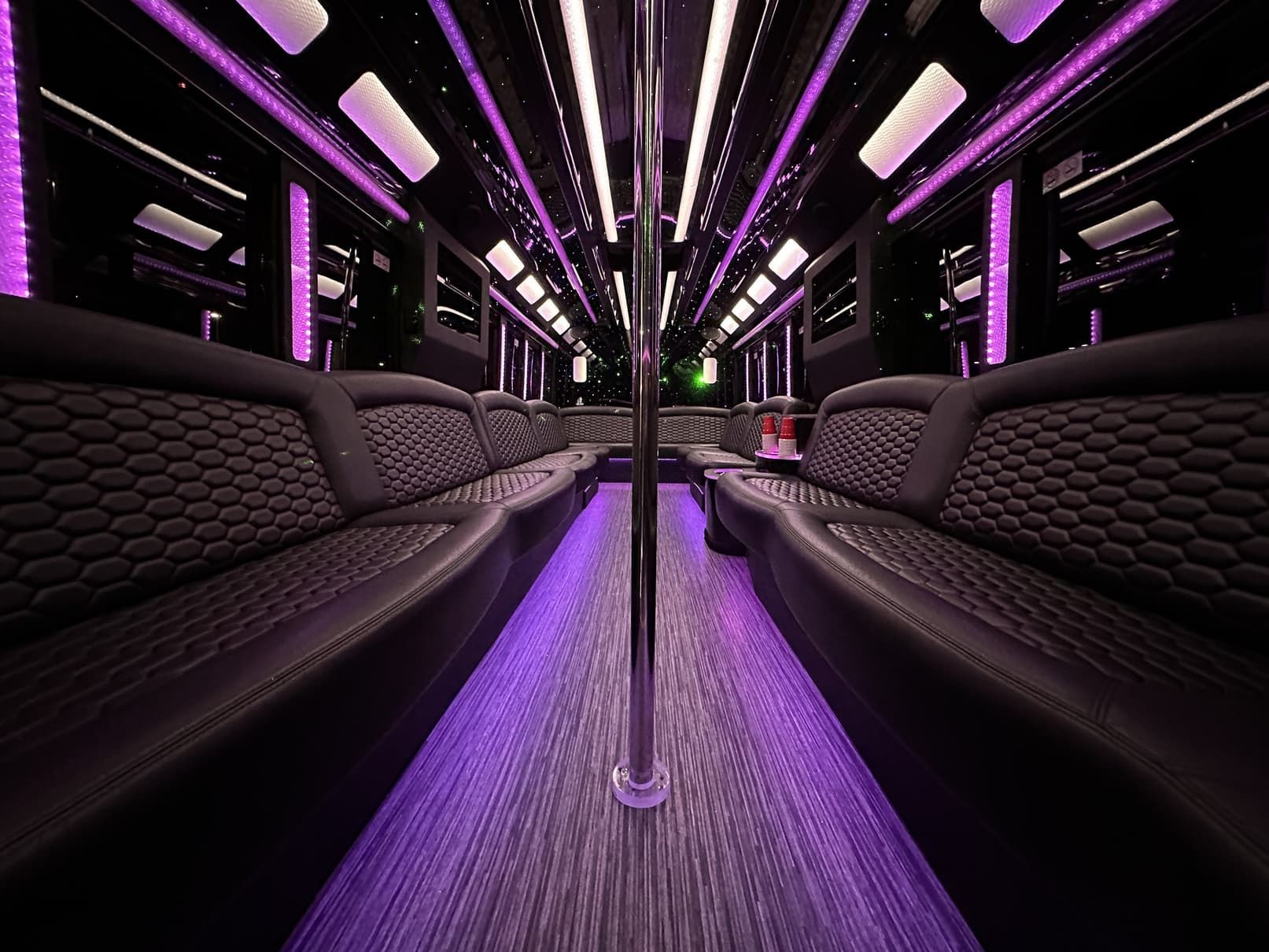 Luxurious interior view of a themed party bus in Las Vegas, featuring vibrant purple lighting and sleek, modern seating designed for exclusive nightlife tours.