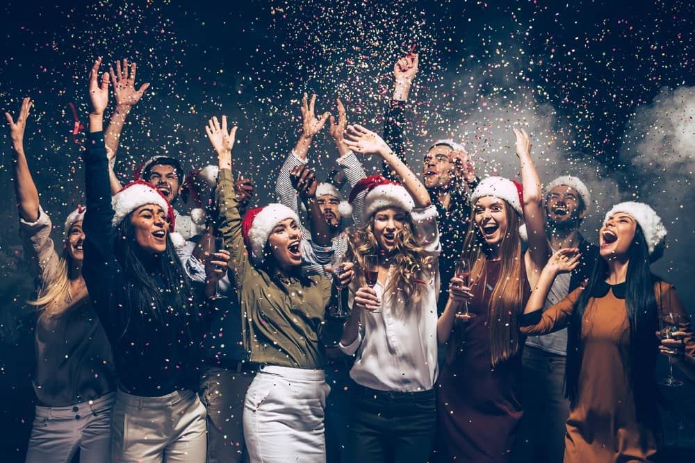 Group celebrating with champagne and party hats under confetti at a custom holiday package event in Las Vegas